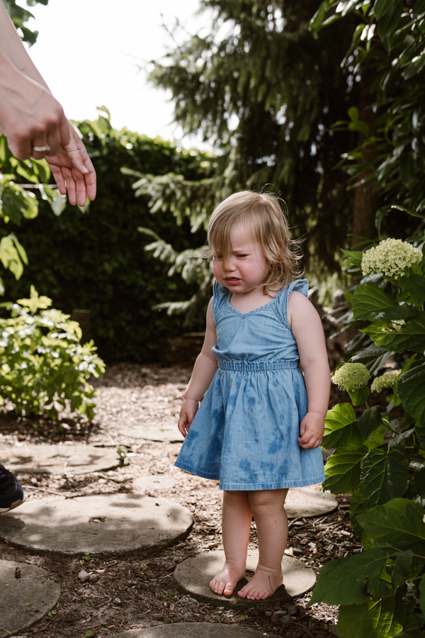 Een verdrietig meisje wordt opgepakt door haar mama tijdens een gezinsshoot in Rijkevoort, Land van Cuijk.