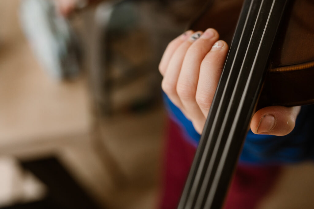 Close-up van de hand van een kind dat viool speelt in tijdens een gezinsfotoshoot in Land van Cuijk