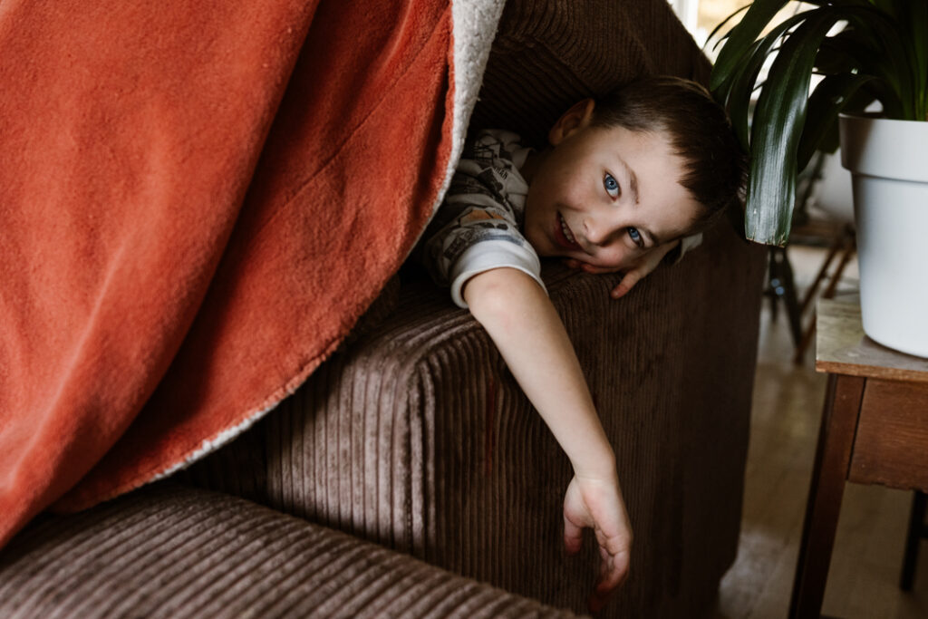 Kind speelt kiekeboe vanuit de hut tijdens een gezinsshoot in Land van Cuijk. 