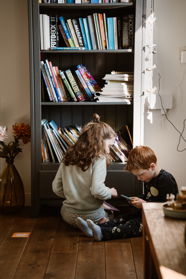 Kinderen zoeken een boekje uit tijdens een gezinsfotoshoot in Land van Cuijk. 