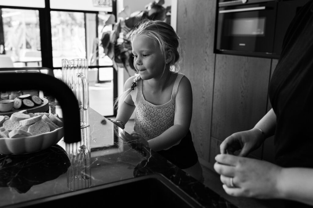 Kindje bereid samen met mama het eten voor tijdens een documentaire gezins fotoshoot in Land van Cuijk