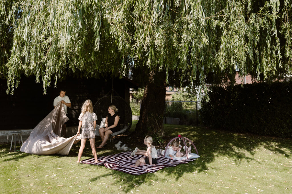 Buiten onder de boom in de tuin picknicken tijdens een documentaire gezinsfotoshoot in Land van Cuijk